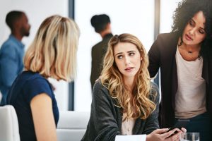 Three women in an office discuss a serious matter