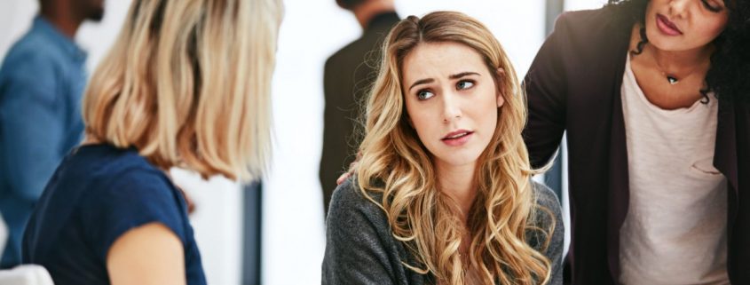 Three women in an office discuss a serious matter